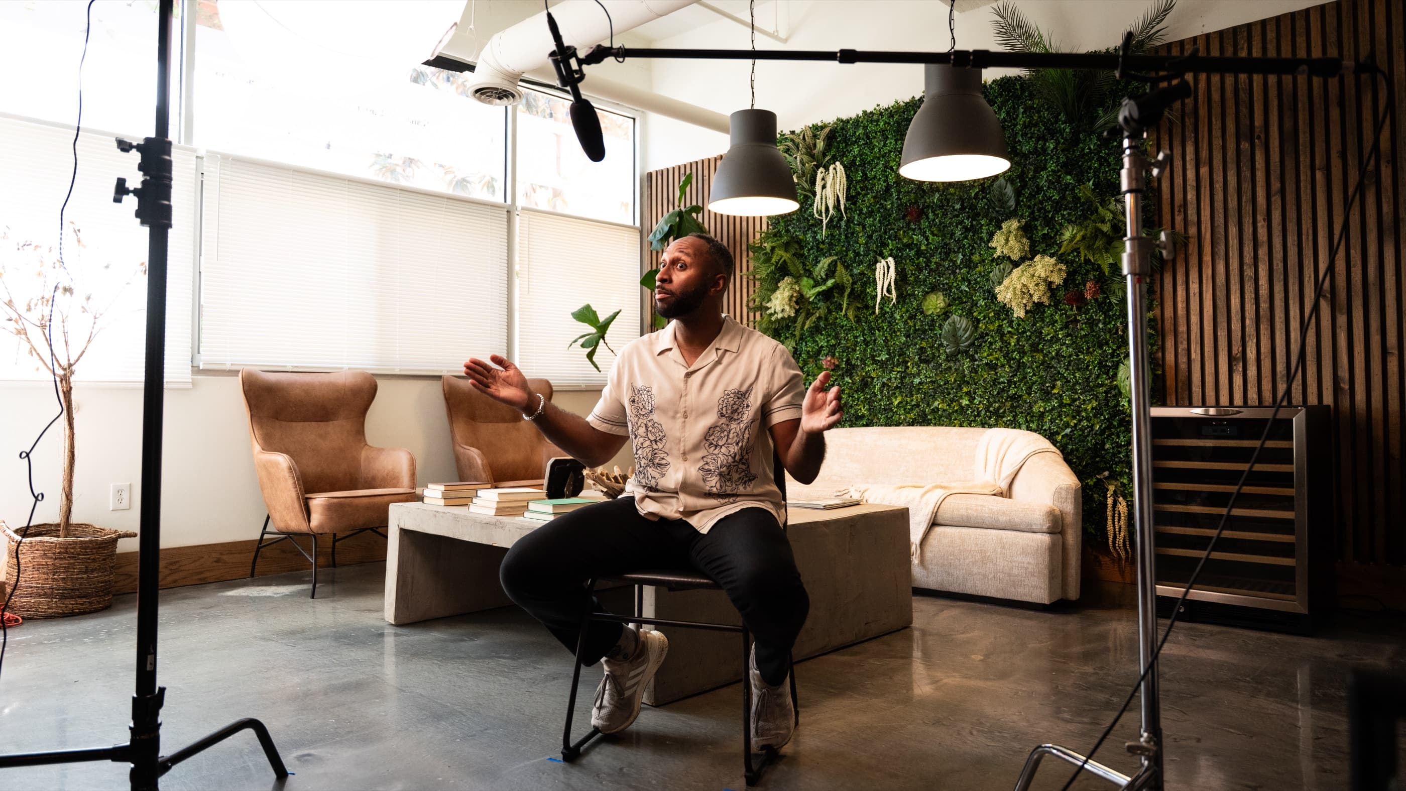 Morgan J. Ingram mid-sentence on a studio set, boom mic overhead and a planted wall behind him.